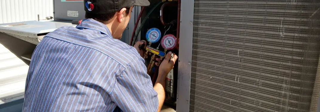 HVAC technician servicing a condenser unit in Bethany
